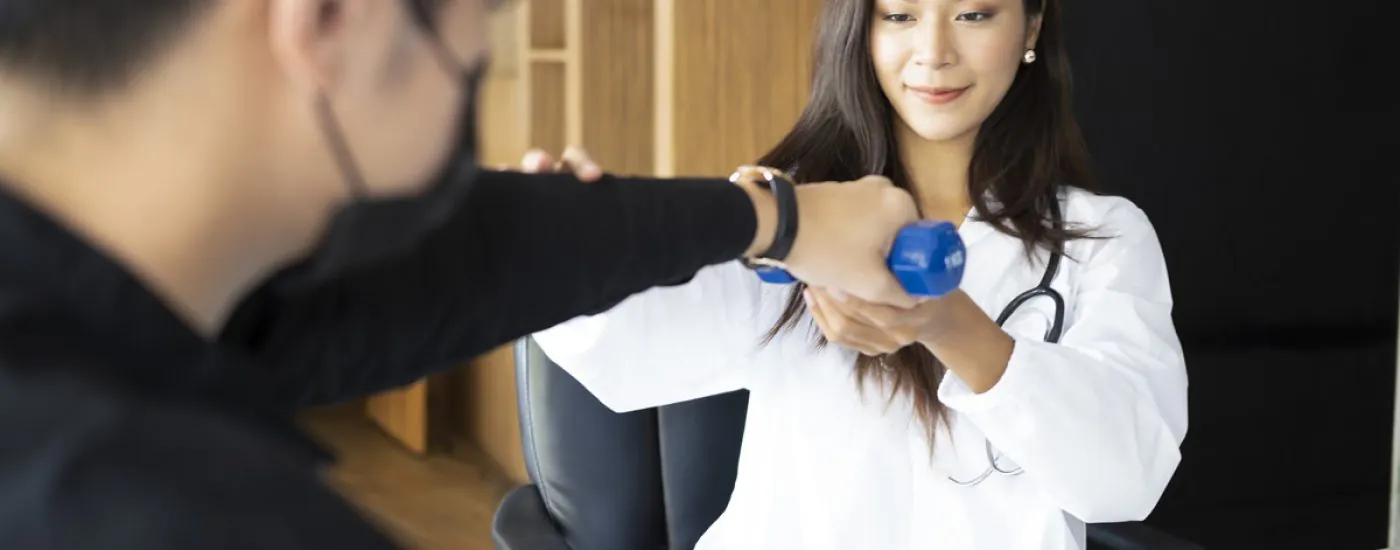 Beautiful woman physiotherapist doing therapeutic exercises for her patient.