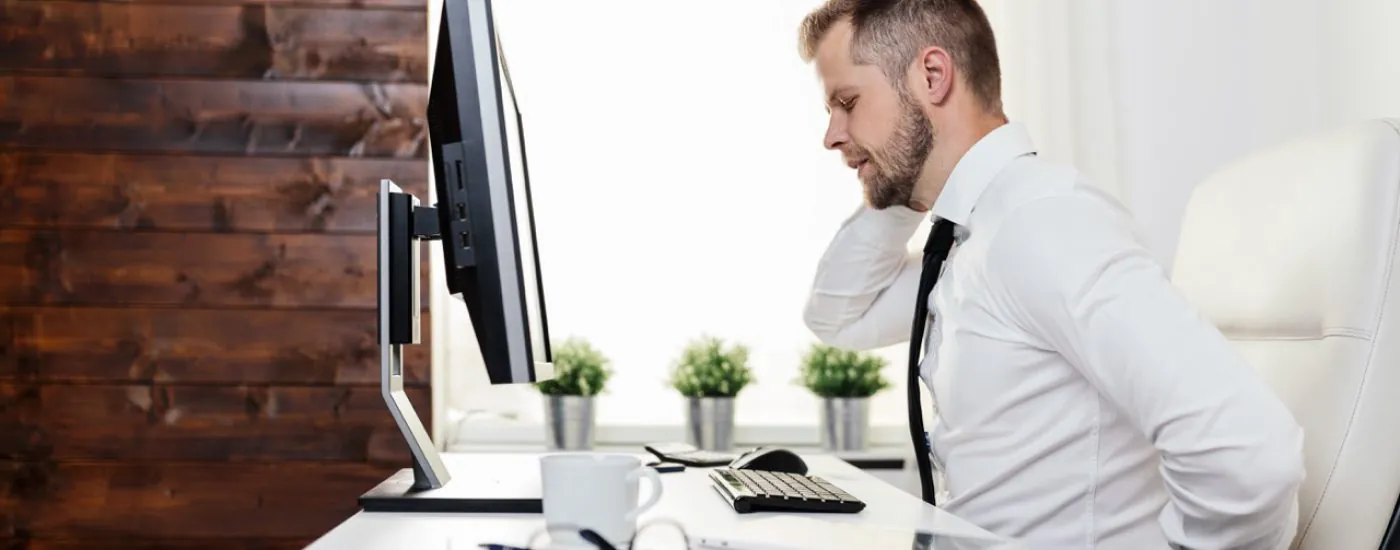 Office worker with back pain from sitting at desk all day